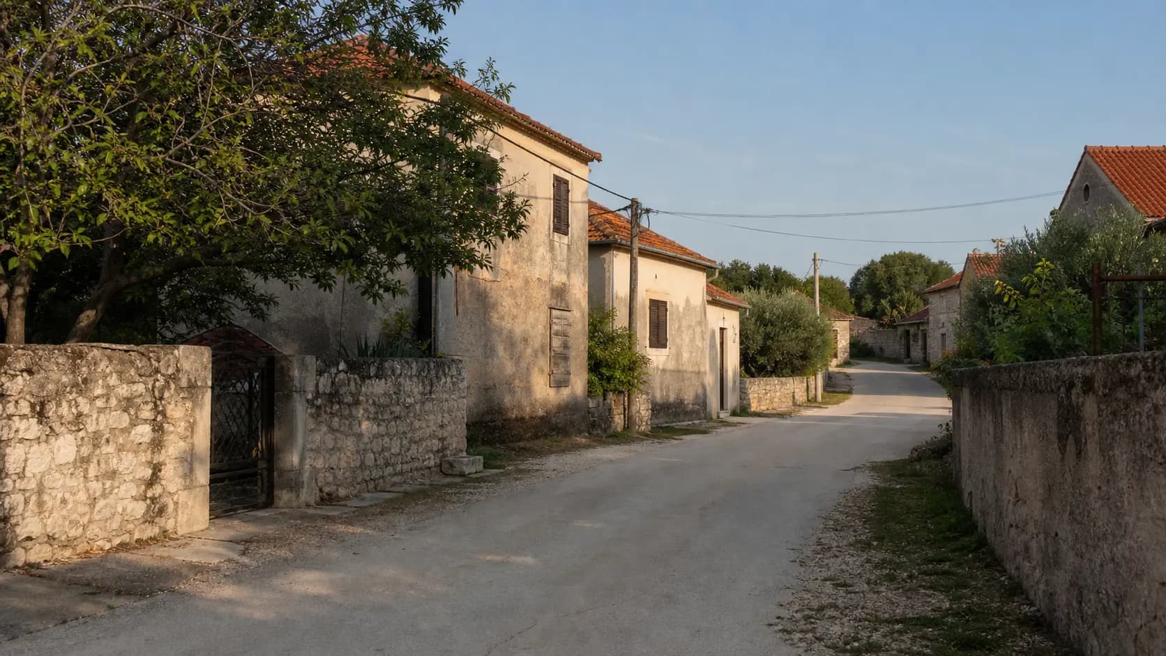 Illustrative quiet village street with stone walls, older facades and Mediterranean greenery in Donje Ceranje.