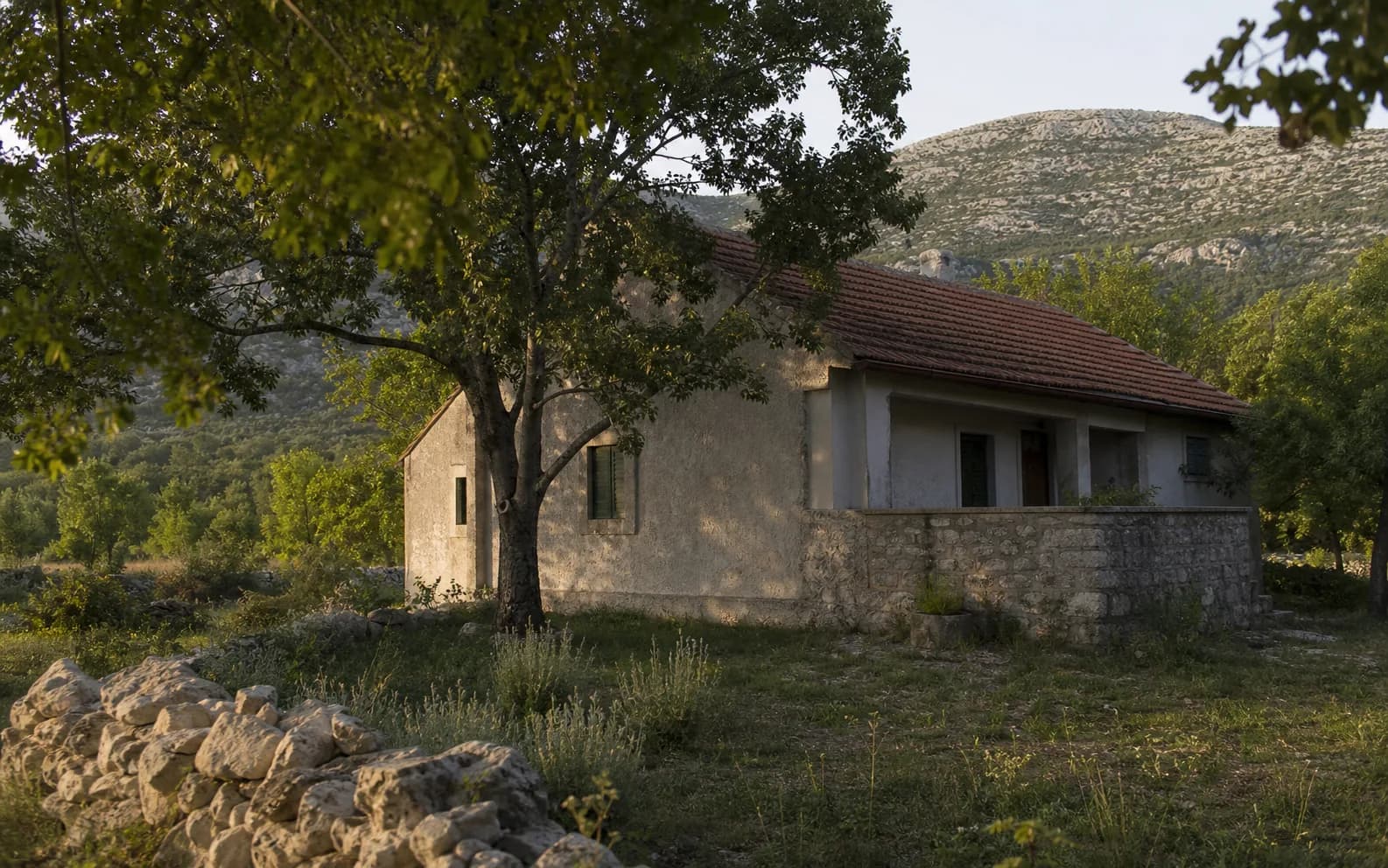 Ilustrativna fotografija za Bruvno, Gračac: stambeni eksterijer uklopljen u otvoreni krajolik.