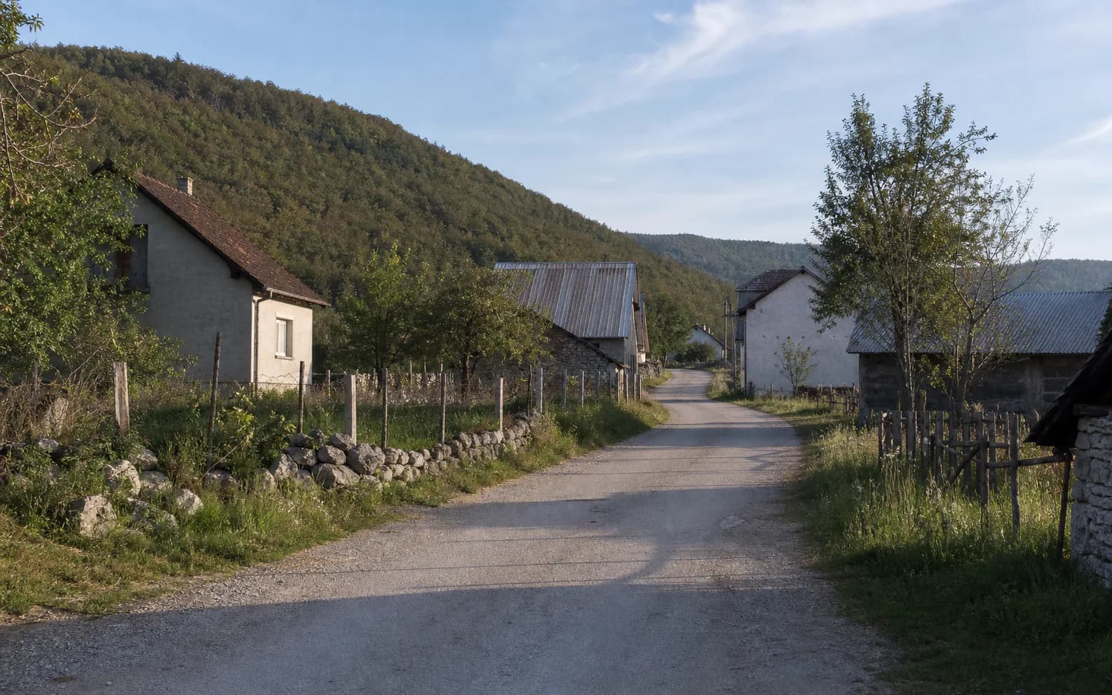 Illustratives Foto für Dabašnica, Gračac: ruhige Siedlungsstraße in hügeliger Umgebung.