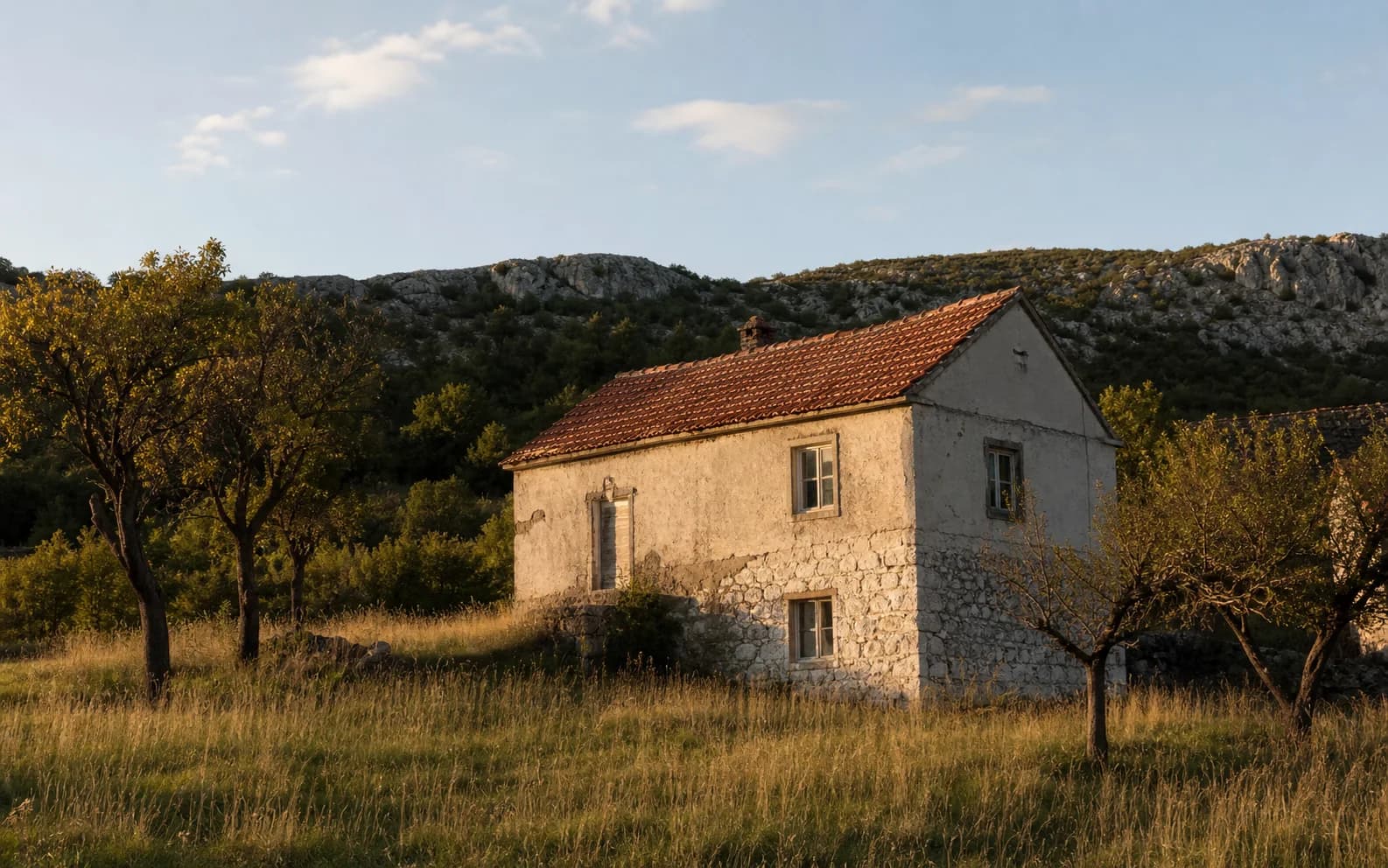 Ilustrativna fotografija za Kom, Gračac: stambeni eksterijer uklopljen u otvoreni krajolik.