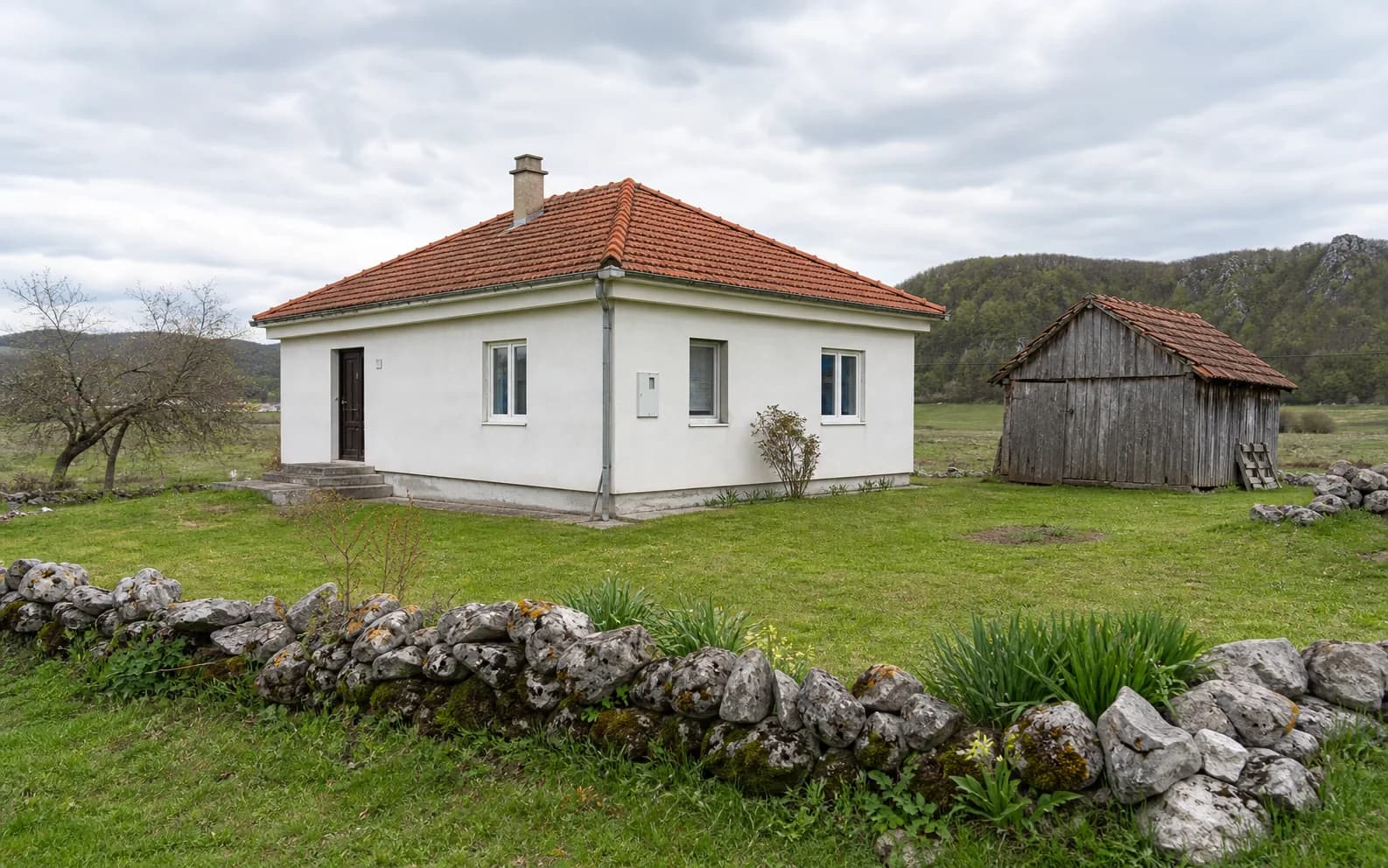 Ilustrativna fotografija za Osredci, Gračac: stambeni eksterijer uklopljen u otvoreni krajolik.