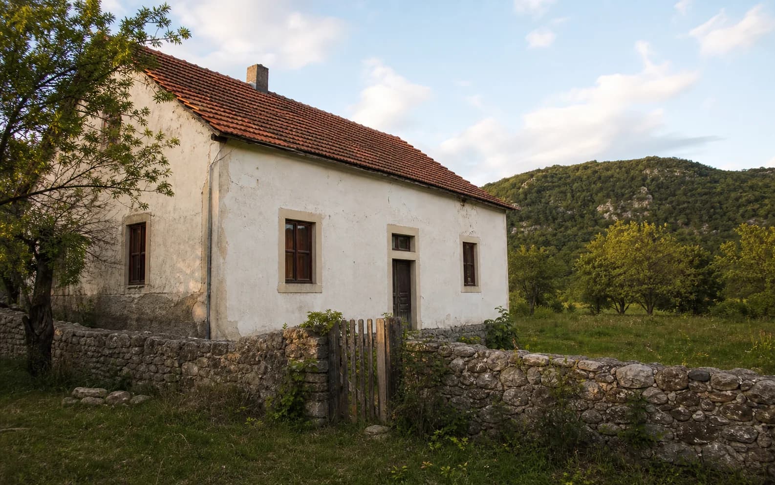 Ilustrativna fotografija za Pribudić, Gračac: stambeni eksterijer uklopljen u otvoreni krajolik.