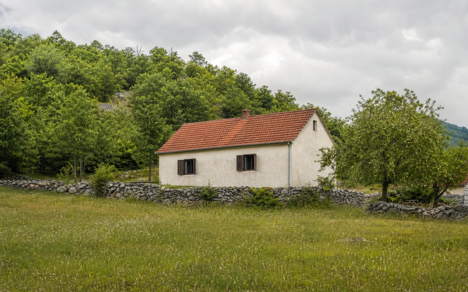 Ilustrativna fotografija za Rastičevo, Gračac: stambeni eksterijer uklopljen u otvoreni krajolik.