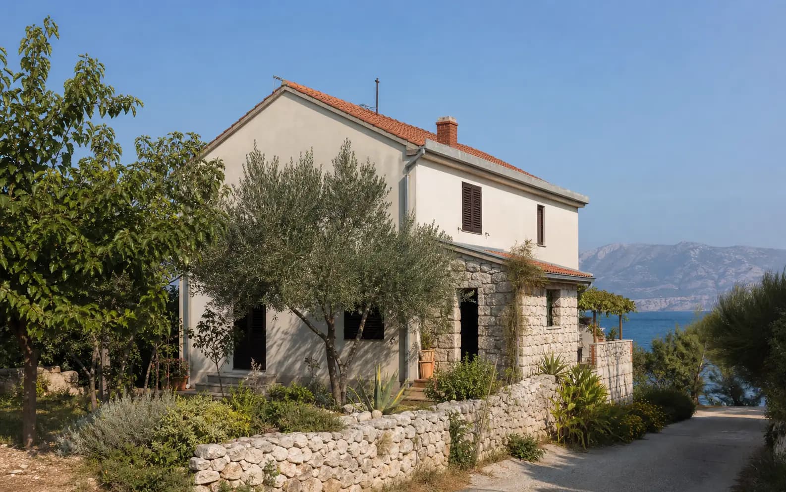 Illustrative residential exterior with stone, olive trees and a coastal outlook in the Vinjerac setting.