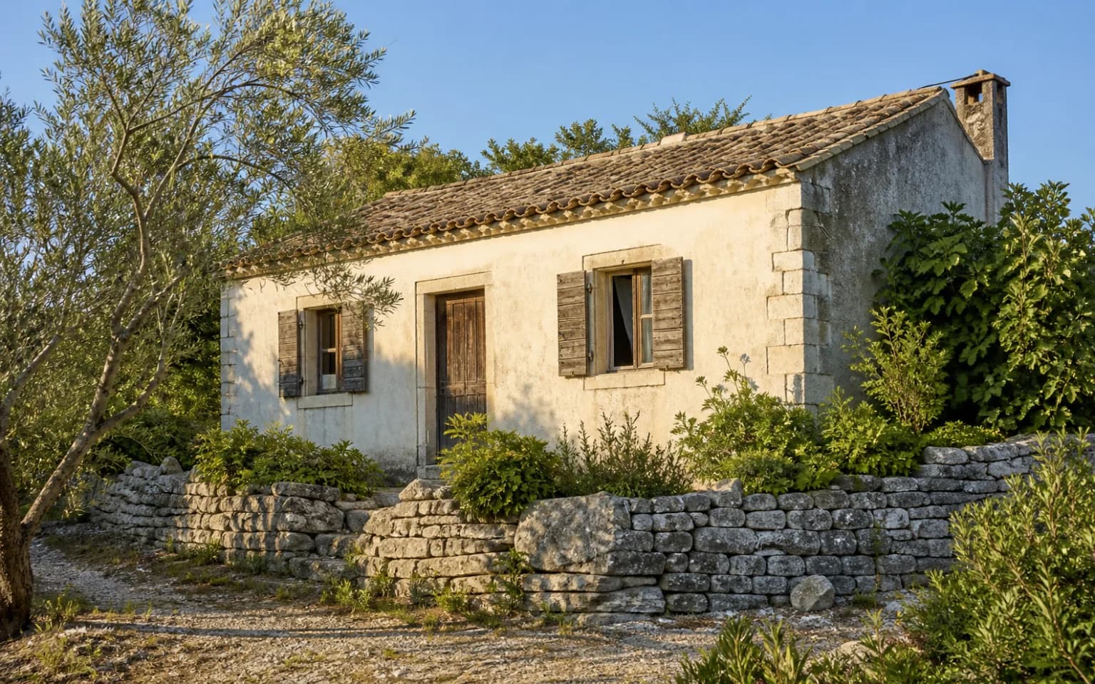 KI-generierte illustrative Außenansicht eines schlichten Inselhauses mit warmer verwitterter Fassade, Holzläden, Olivenbaum und Trockenmauer im Ambiente von Savar.