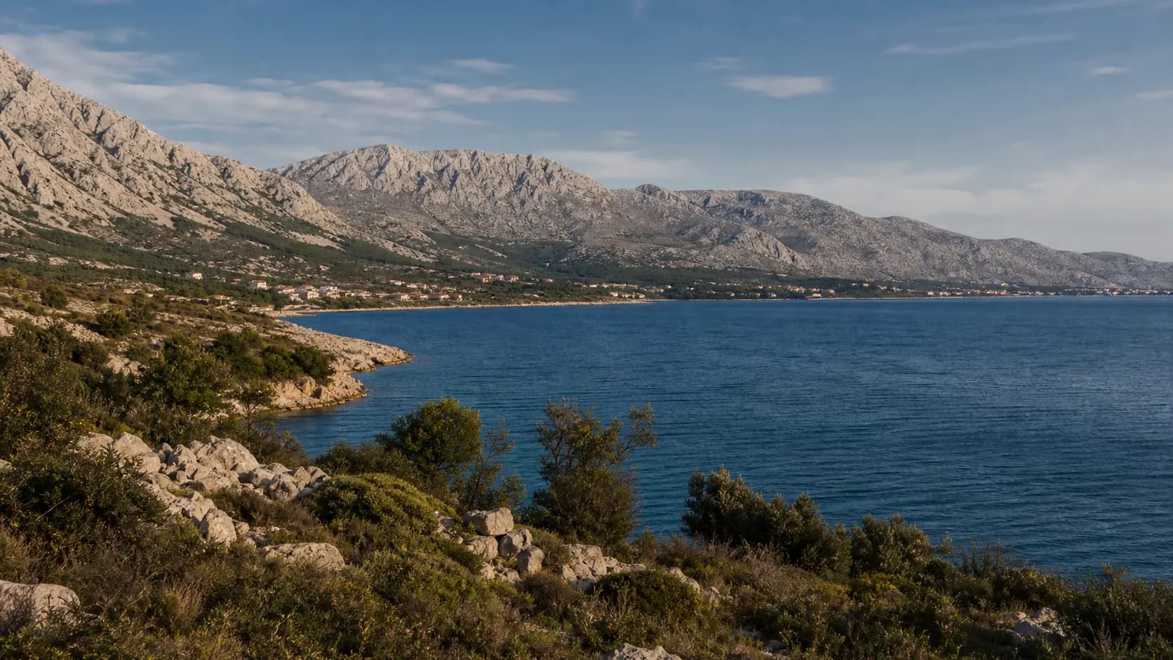 Ilustrativni široki pogled na stjenovitu obalu i Velebit iznad plavog mora za Starigrad.
