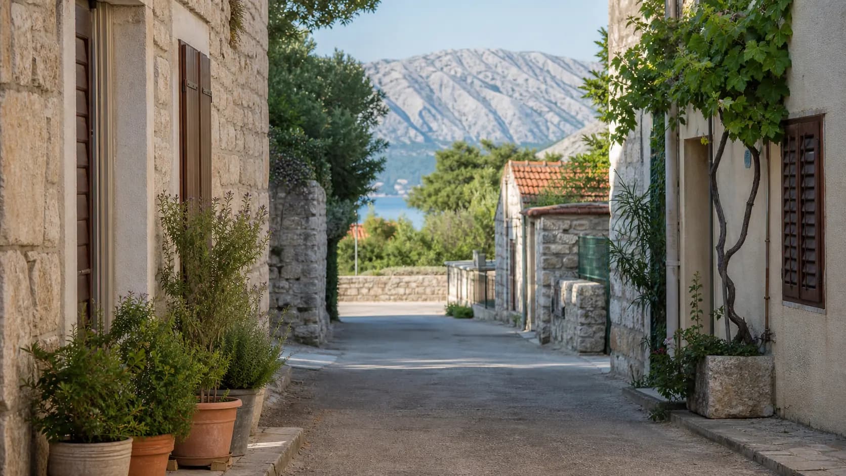 Ilustrativna kamena ulica s mediteranskim zelenilom i pogledom prema Velebitu za Starigrad.