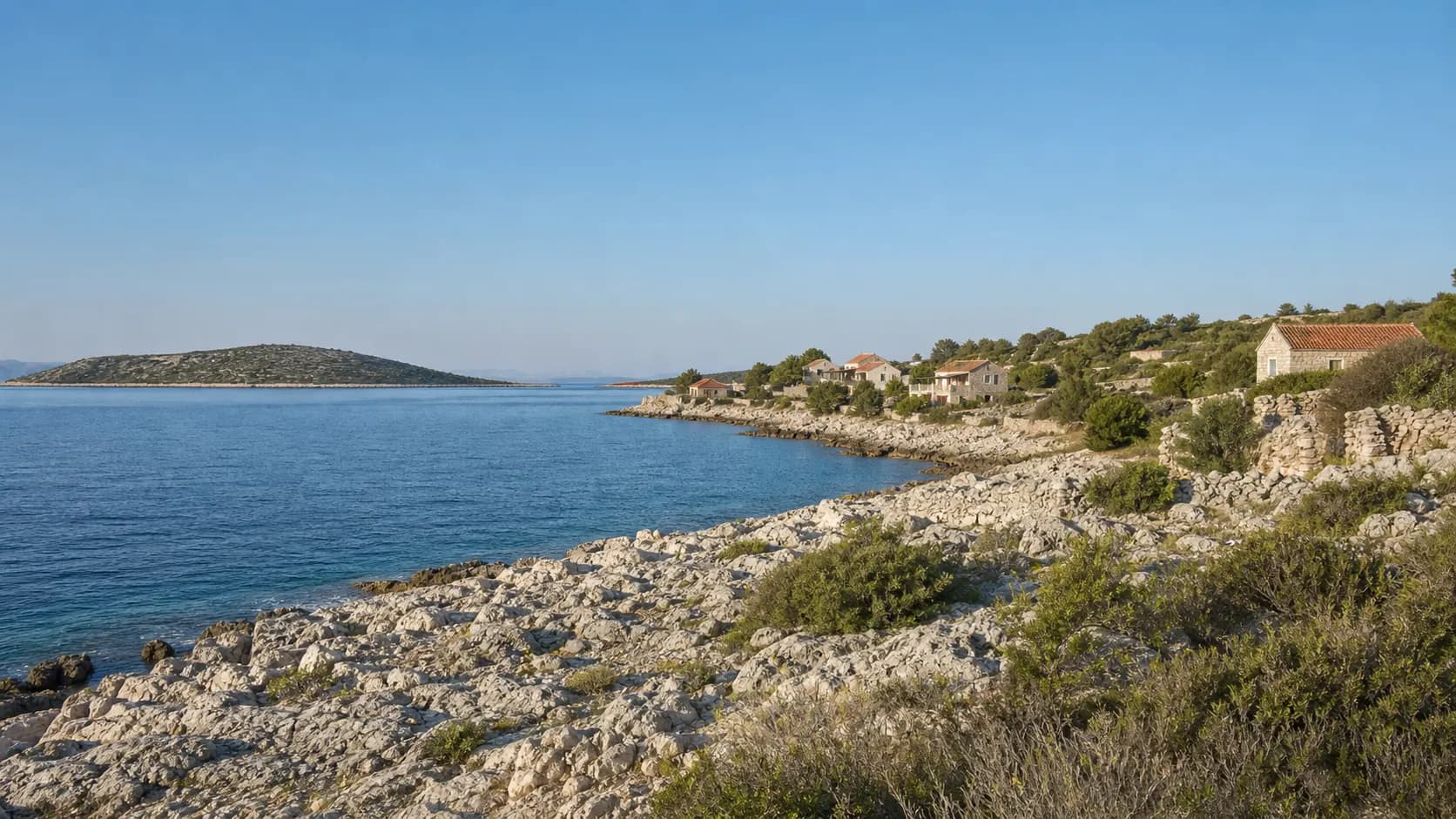 Ilustrativni široki pogled na kamenitu obalu, skromne kuće i otočni krajolik Babca.