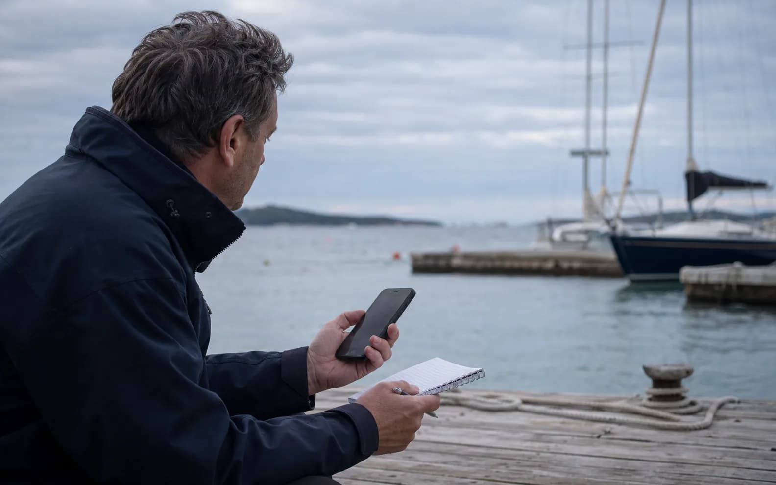 Vlasnik plovila pregledava opće uvjete na telefonu uz neutralan gat, bez prikaza konkretne marine.