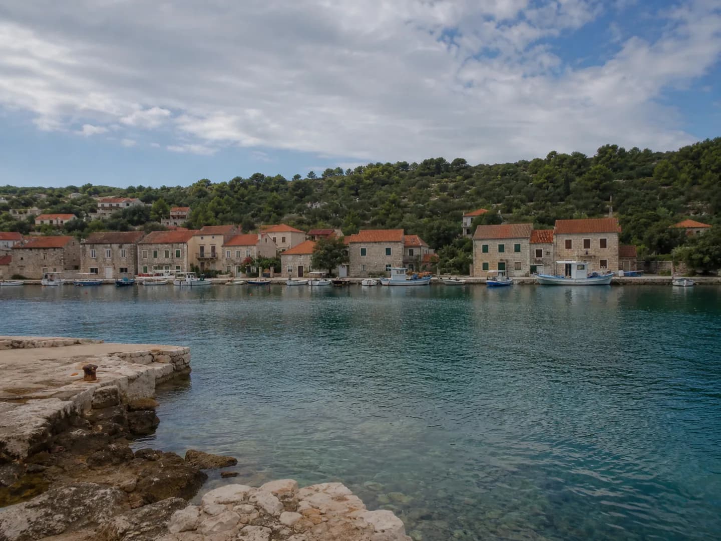 Mirna otočna luka u Salima na Dugom otoku s kamenim kućama i malim plovilima.