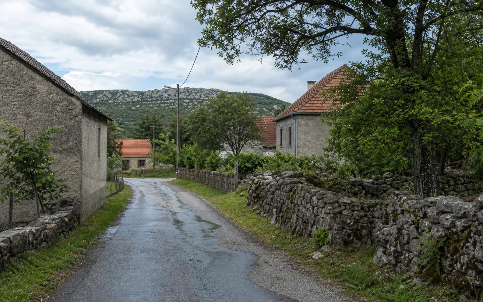 Ilustrativna fotografija za Begluci, Gračac: mirna ulica naselja u brdskom okruženju.