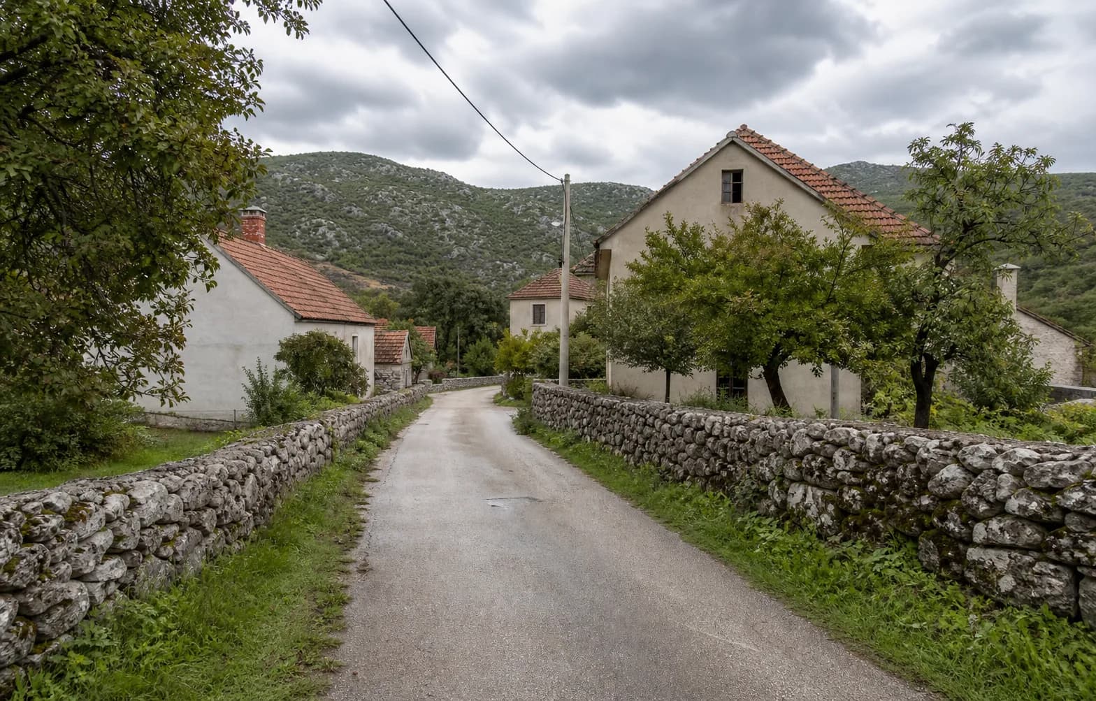 Ilustrativna fotografija za Brotnja, Gračac: mirna ulica naselja u brdskom okruženju.