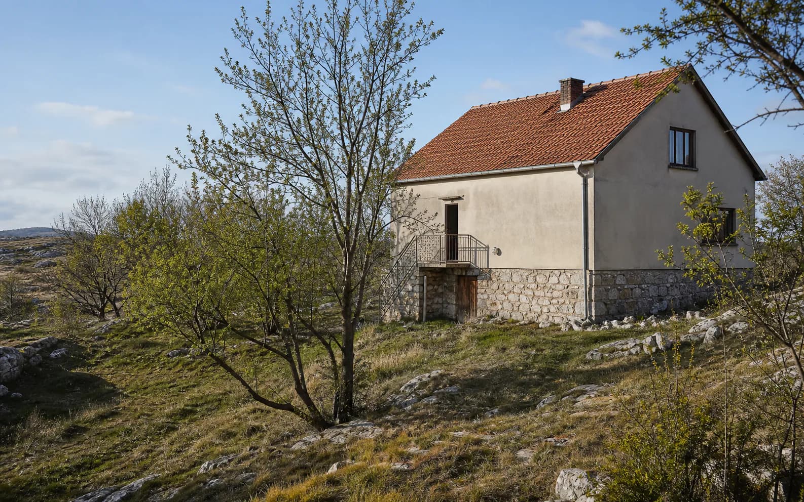Ilustrativna fotografija za Cerovac, Gračac: stambeni eksterijer uklopljen u otvoreni krajolik.