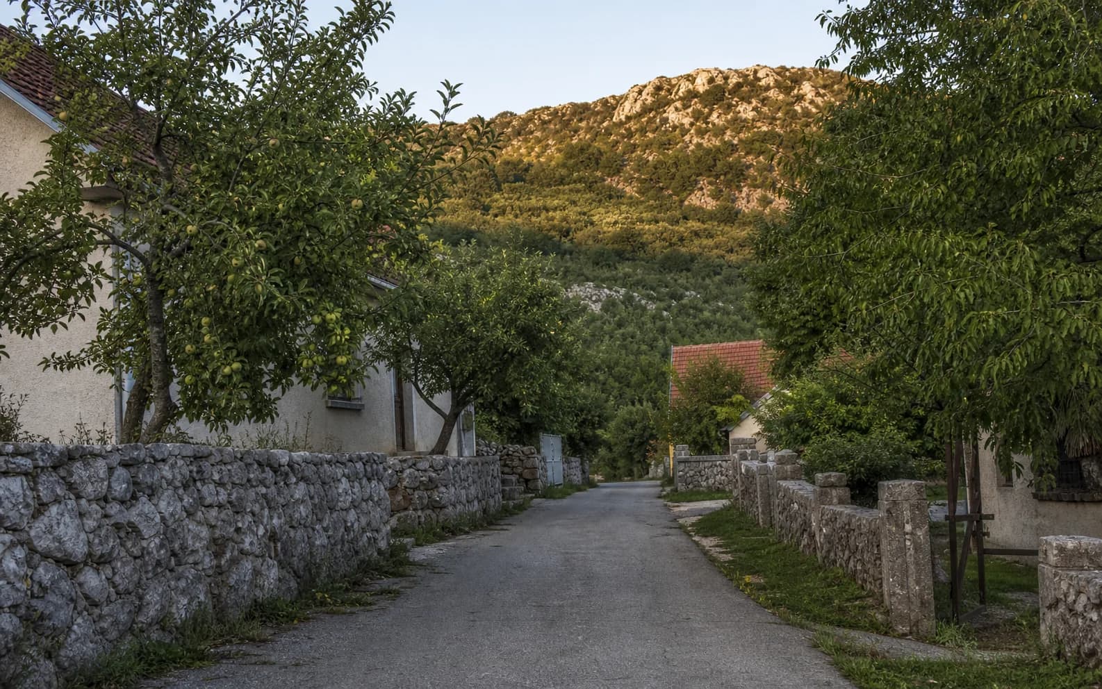 Ilustrativna fotografija za Duboki Dol, Gračac: mirna ulica naselja u brdskom okruženju.