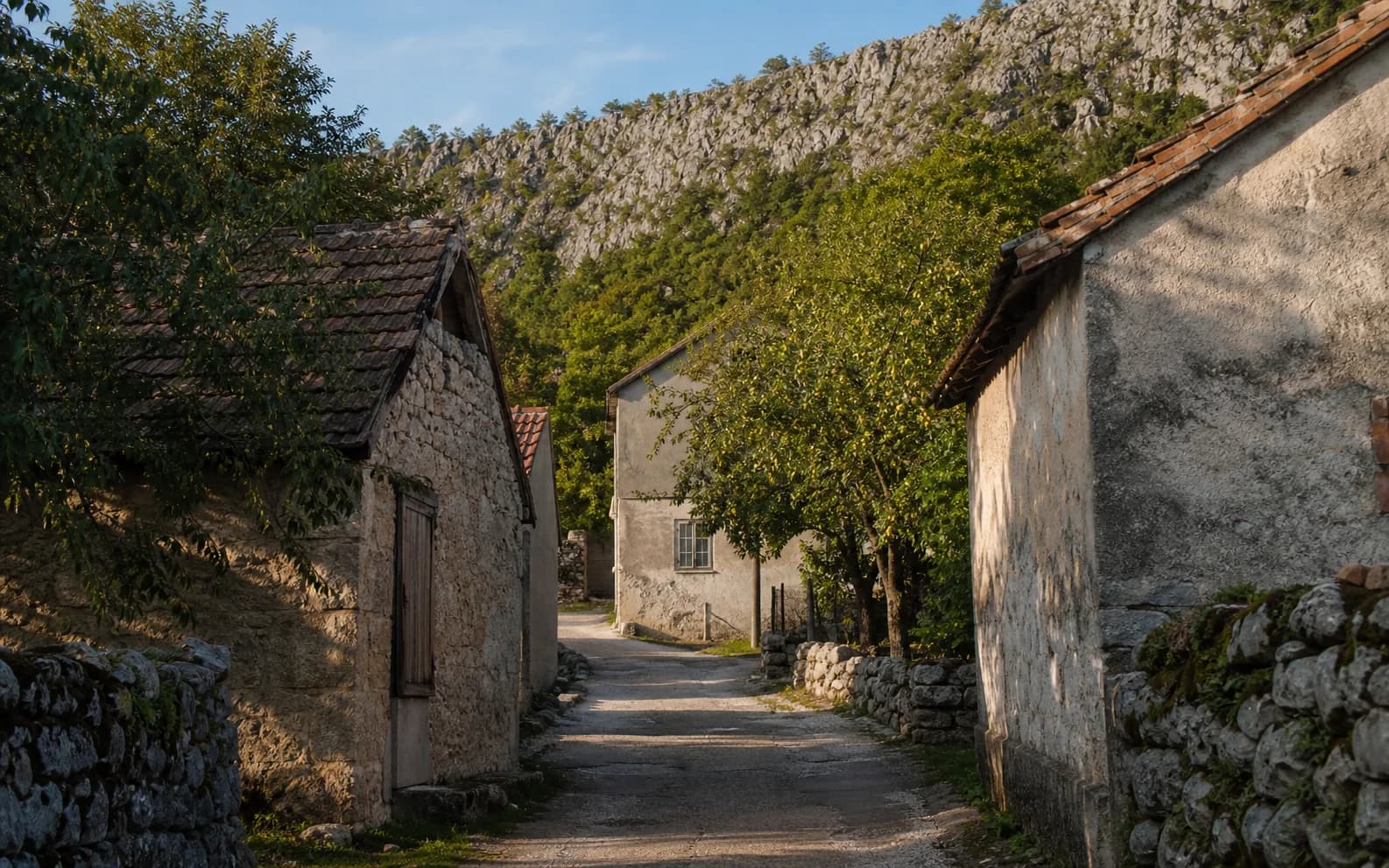 Ilustrativna fotografija za Grab, Gračac: mirna ulica naselja u brdskom okruženju.