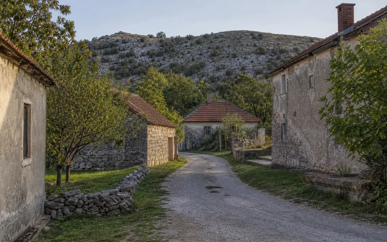 Ilustrativna fotografija za Neteka, Gračac: mirna ulica naselja u brdskom okruženju.