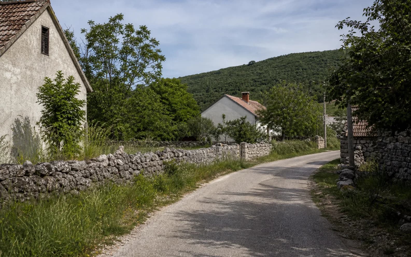 Ilustrativna fotografija za Otrić, Gračac: mirna ulica naselja u brdskom okruženju.