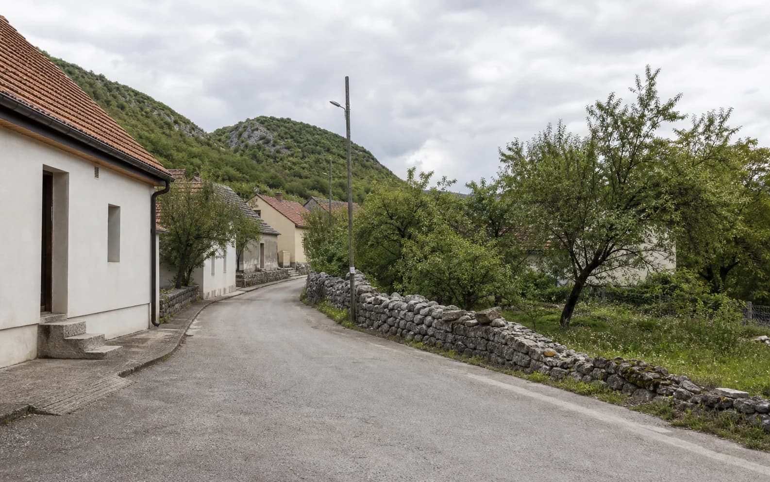 Ilustrativna fotografija za Srb, Gračac: mirna ulica naselja u brdskom okruženju.