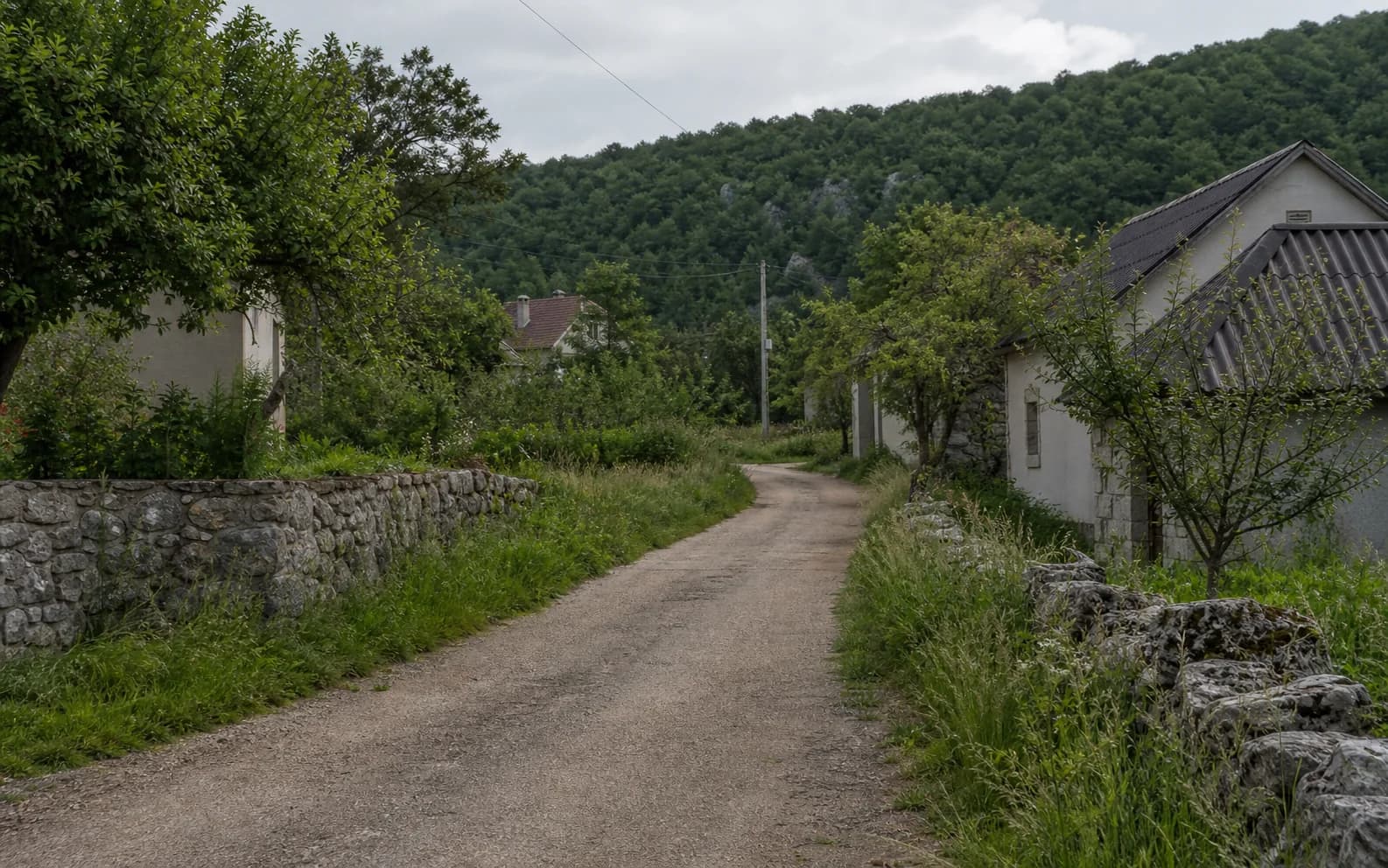 Ilustrativna fotografija za Tiškovac Lički, Gračac: mirna ulica naselja u brdskom okruženju.
