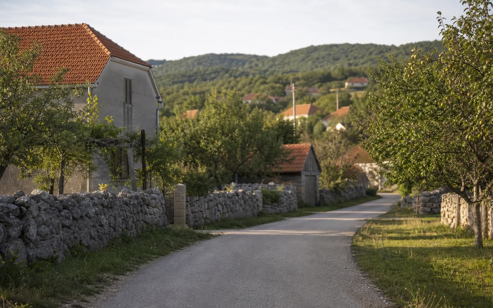 Ilustrativna fotografija za Tomingaj, Gračac: mirna ulica naselja u brdskom okruženju.