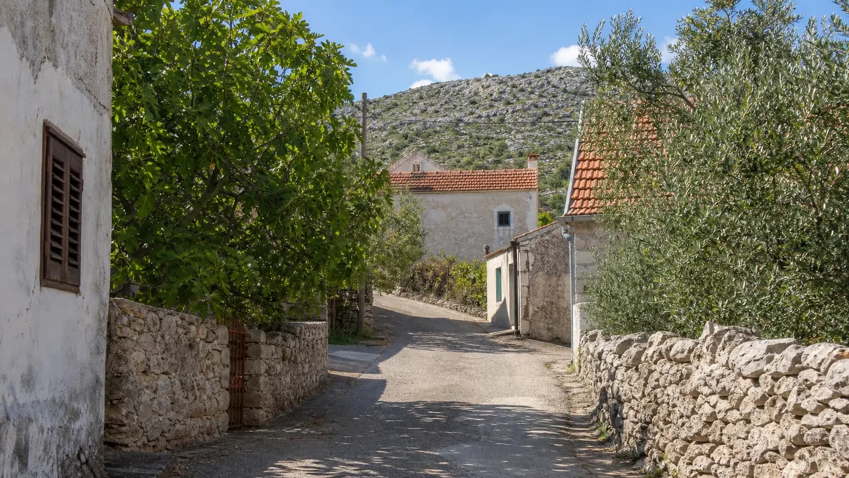 Illustrative ruhige Dorfgasse zwischen Steinhäusern und mediterranem Grün für Jasenice.
