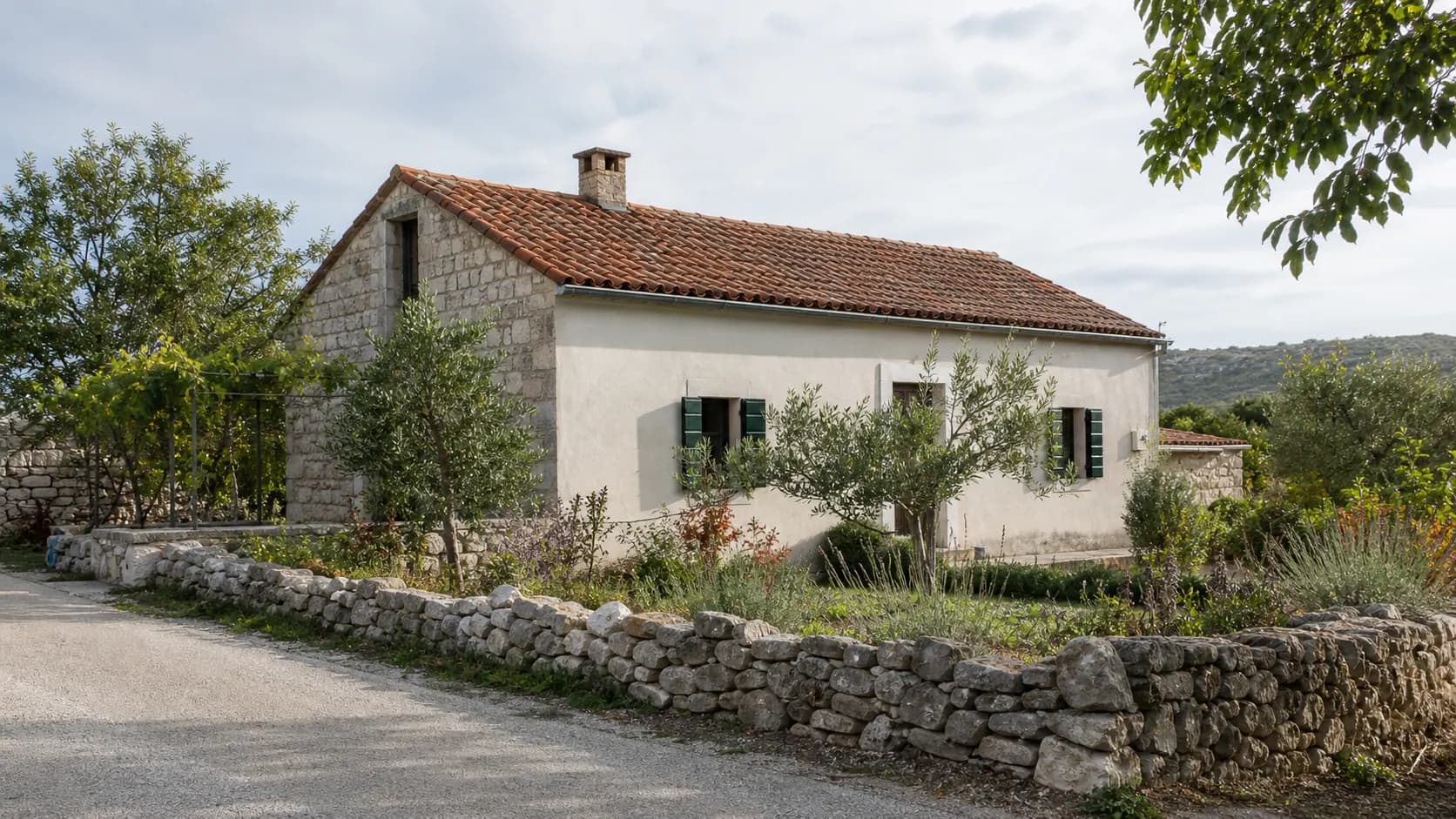 Illustrative residential exterior with a stone facade, dry-stone wall and natural Mediterranean garden in the Bogatnik setting.