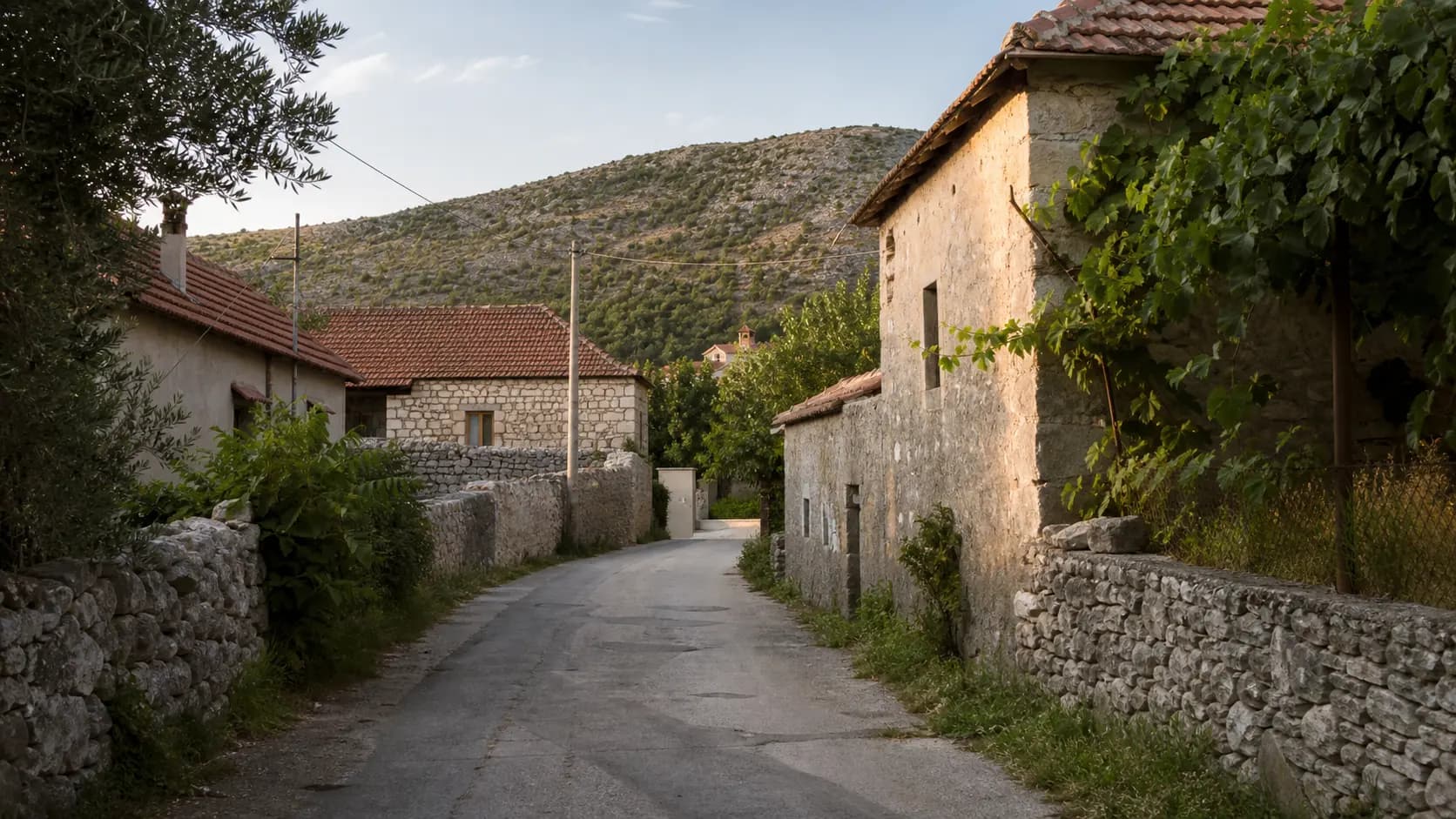 Illustrative village lane in Kruševo, with stone homes, dry-stone walls and low karst hills.