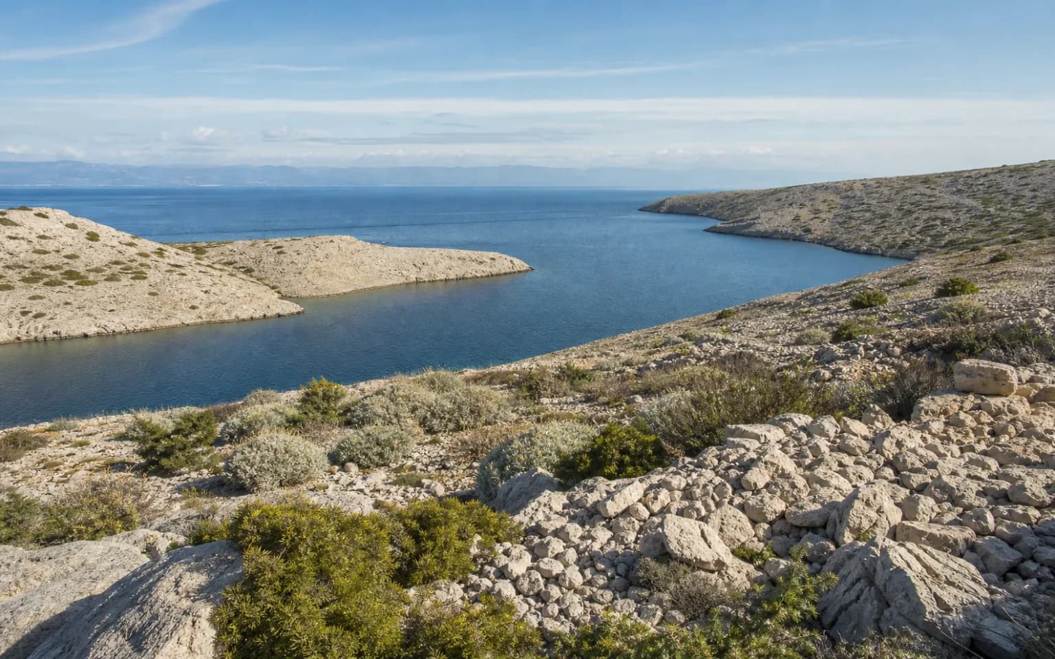 KI-generierter illustrativer Weitblick auf eine ruhige Inselbucht, hellen Stein und niedrige mediterrane Vegetation im Ambiente von Dinjiška.