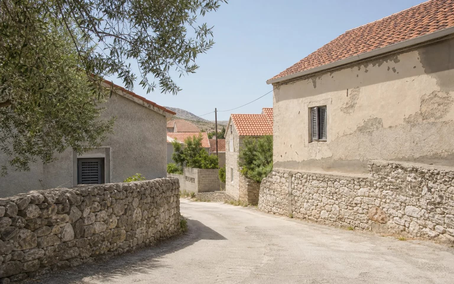 KI-generierte illustrative Dorfstraße mit Trockenmauer, einfachen Häusern und einem Olivenbaum im Ambiente von Dinjiška.