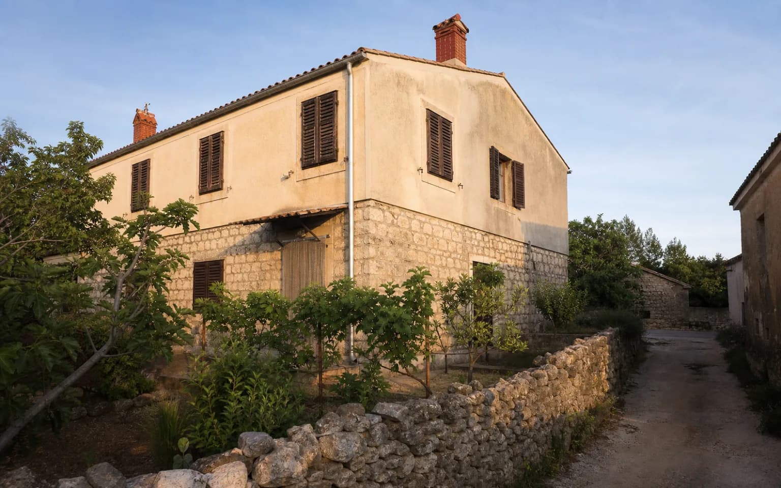 KI-generierte illustrative Außenansicht eines bescheidenen Inselhauses mit Steinsockel, Fensterläden und kleinem Garten im Ambiente von Miškovići.
