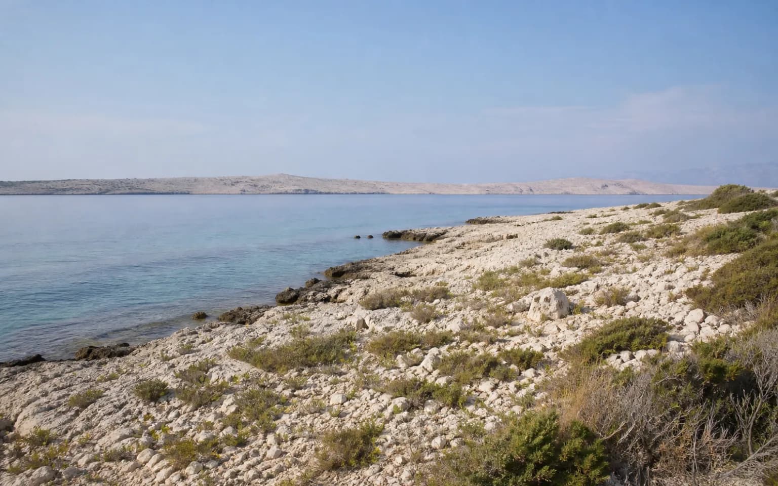 AI-generated illustrative view of a quiet rocky island coast, low Mediterranean vegetation and sea in the Šimuni, Pag setting.