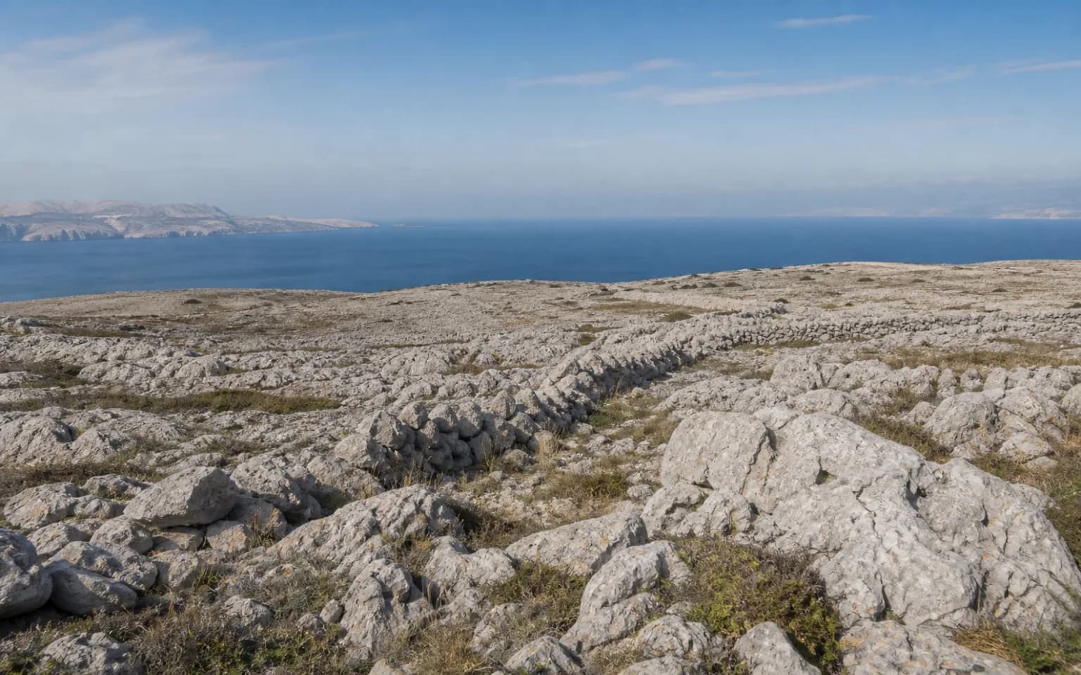 AI-generated illustrative wide view of pale island karst, a dry-stone wall and sea in the Vrčići, Pag setting.