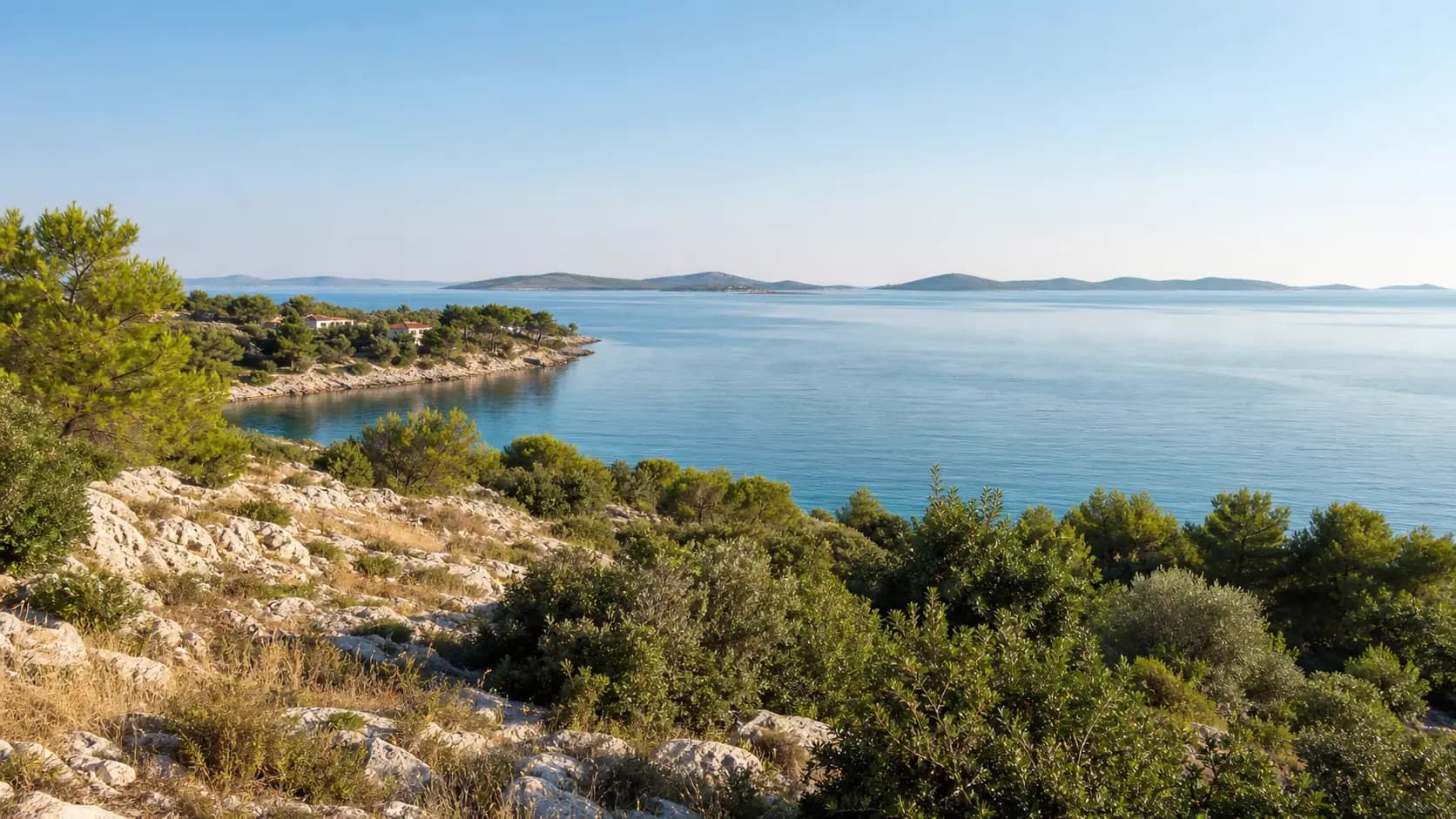 Ilustrativni široki pogled na kamenitu obalu, borove i otočni horizont na području Draga.