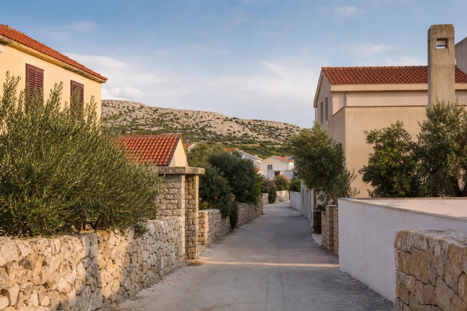 Illustrative ruhige Inselgasse mit Steinmauern und mediterranen Häusern in Povljana.